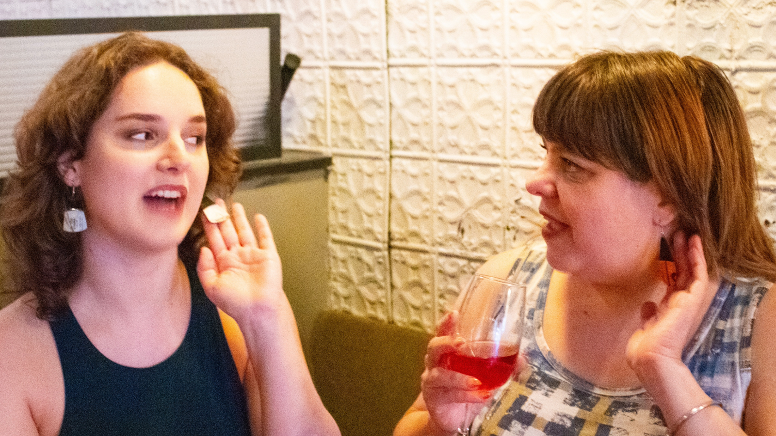 Two women talking and sharing a joyful reaction to reVinyled jewelry