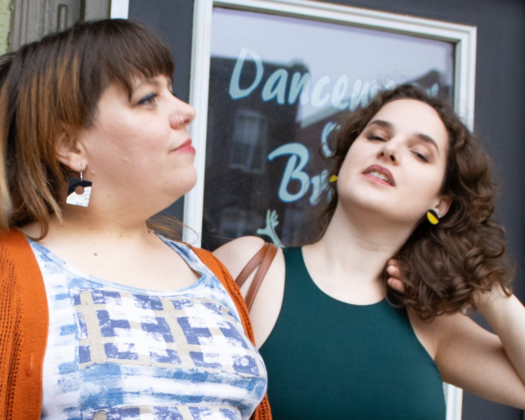 Two people wearing colorful reVinyled vinyl record earrings