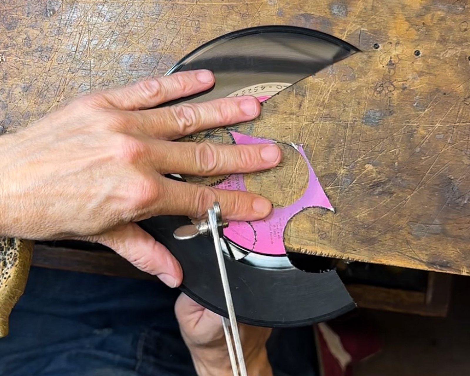 Cutting a rescued vinyl record individually with a traditional jeweler's saw