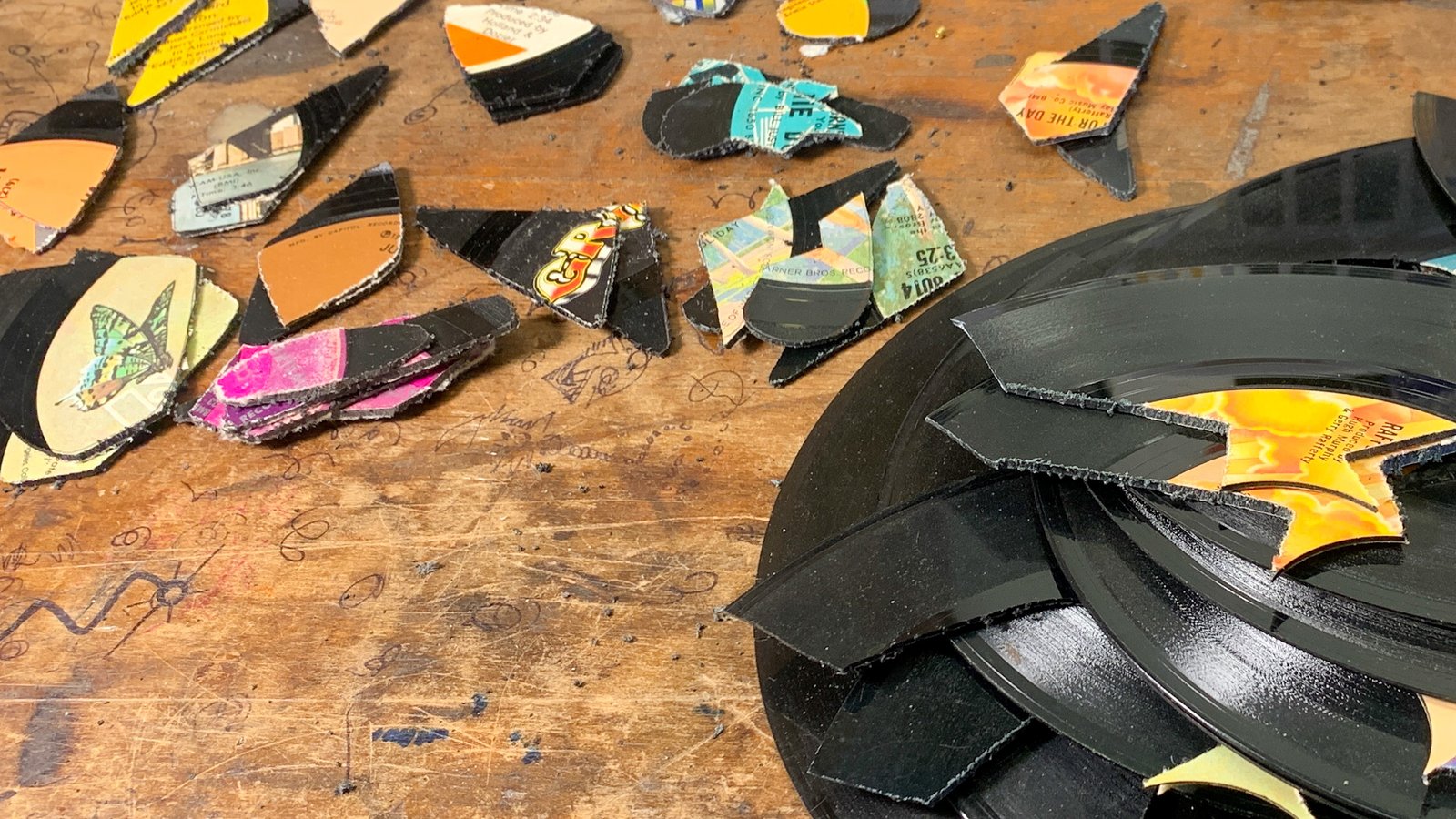 Cut vinyl records and colorful record label pieces on the reVinyled workbench
