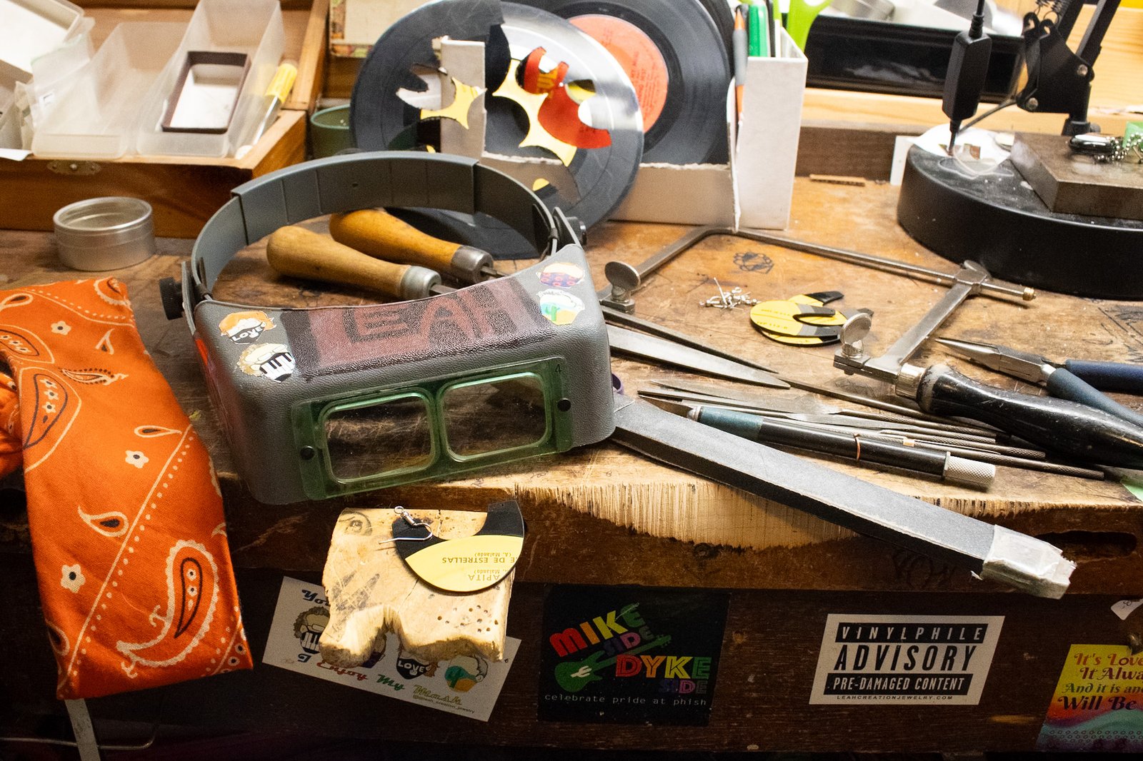 The reVinyled jewelry bench with traditional hand tools, rescued vinyl records, and pieces in progress